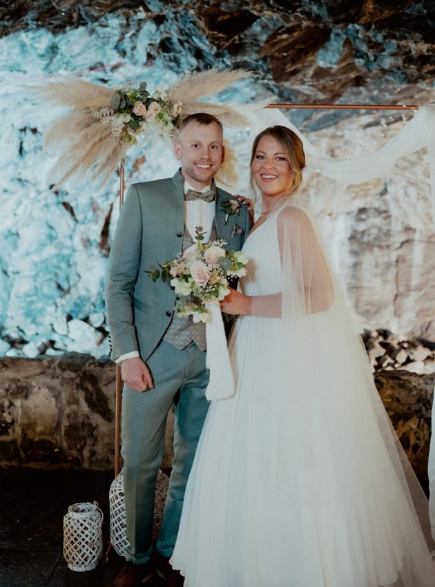 ein Mann und eine Frau in klassischer westlicher Hochzeitskleidung: Er in einem eleganten Gehrock, sie in einem weiten Hochzeitskleid und Schleier.